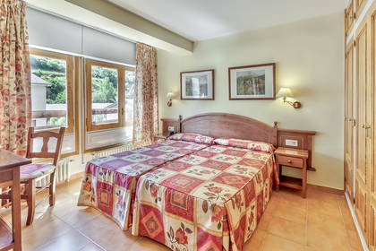 Pokój hotelowy z dwoma pojedynczymi łóżkami, szafą i oknem.