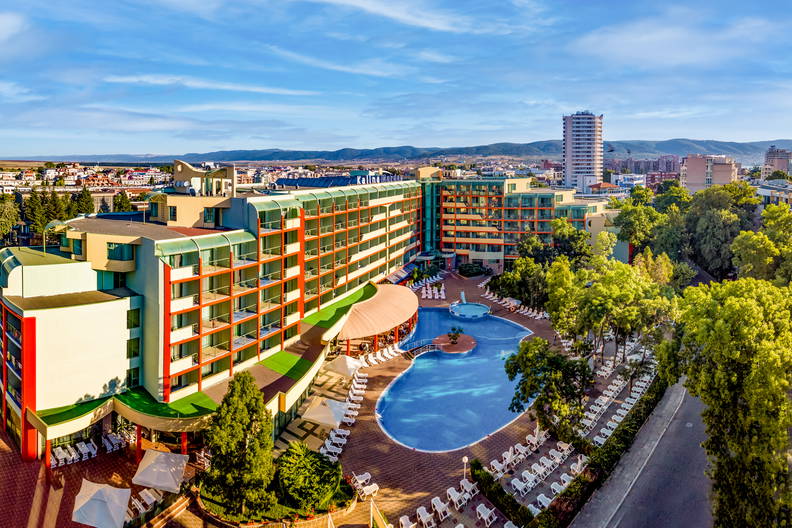Hotel z basenem i leżakami w słoneczny dzień (widok z góry).
