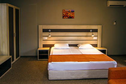 Pokój hotelowy z łóżkiem, szafą i pomarańczową sofą.