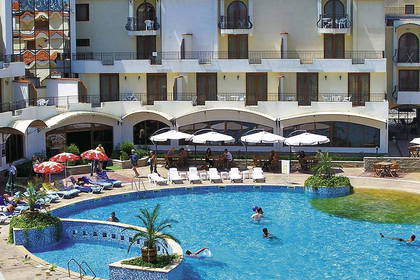 Widok z góry na basen hotelowy z parasolami, leżakami i kąpiącymi się osobami.