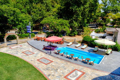 Hotel z basenem, leżakami i parasolami, widok z góry.