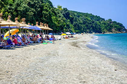 Słoneczna plaża z leżakami i parasolami.