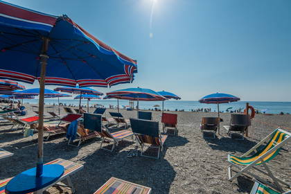Plaża z parasolami i leżakami w słoneczny dzień.