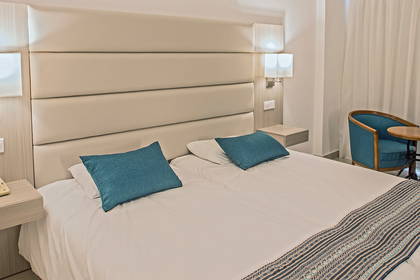 Pokój hotelowy z łóżkiem, fotelami i stolikiem.