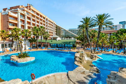 Hotel z basenem otoczonym palmami.