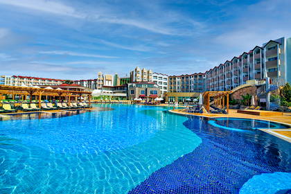 Kompleks hotelowy z basenem i leżakami do opalania.