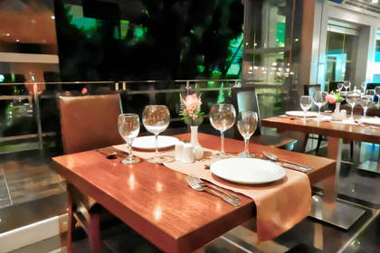 Stół w restauracji nakryty do posiłku, ozdobiony kwiatami.