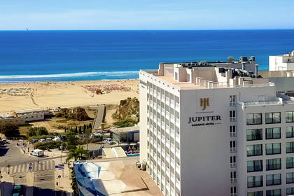 Słoneczny widok z góry na hotel Jupiter Algarve, piaszczystą plażę i błękitny ocean.