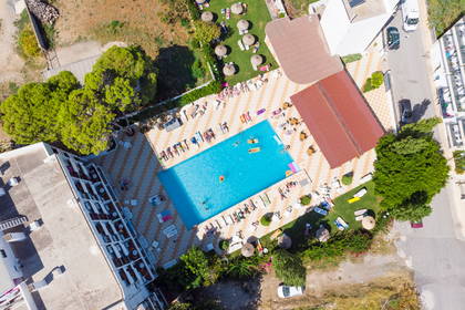Zdjęcie z lotu ptaka: hotel z basenem, leżakami i zielenią.