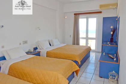 Pokój hotelowy z trzema łóżkami, niebieską szafką i balkonem.
