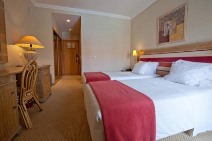 Pokój hotelowy z dwoma łóżkami, biurkiem i krzesłem.