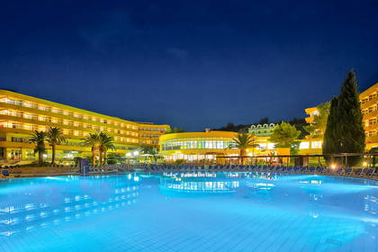 Hotel z basenem oświetlonym na niebiesko nocą.