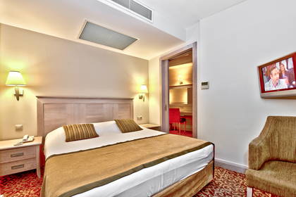 Pokój hotelowy z łóżkiem, telewizorem i krzesłem.