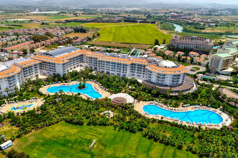 Widok z lotu ptaka na luksusowy hotel z basenami i zielenią.