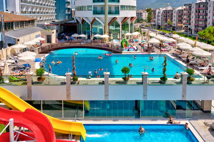 Kompleks hotelowy z basenami i zjeżdżalniami w słoneczny dzień.