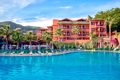 Hotel z basenem, leżakami i palmami.