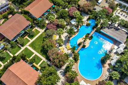 Resort z basenem, budynkami i zielenią, widziany z lotu ptaka.