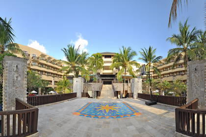 Hotel otoczony palmami, z basenem w tle.
