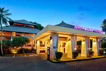 Fasada hotelu Mercure z podjazdem i zielenią wokół.
