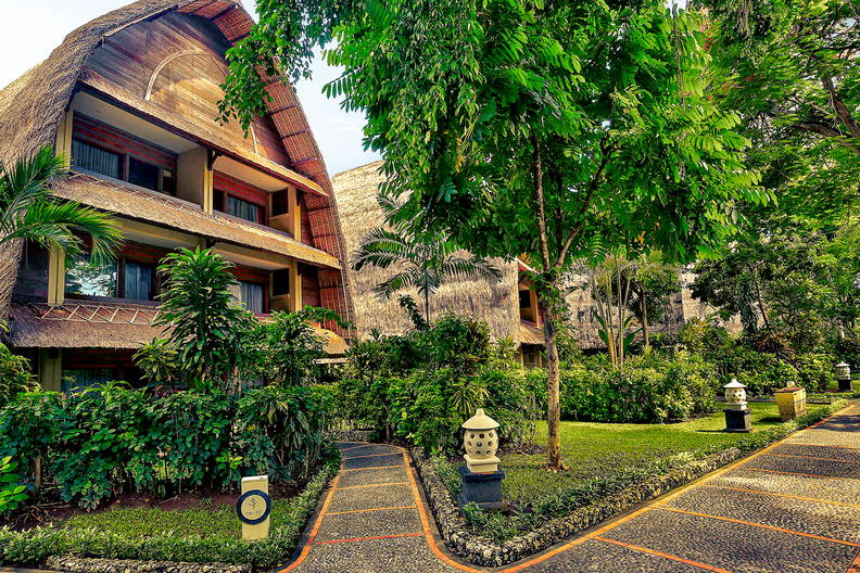 Hotel w tropikalnym ogrodzie z kamiennymi ścieżkami.