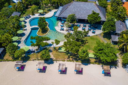Zdjęcie lotnicze plaży z parasolami, basenu i restauracji.