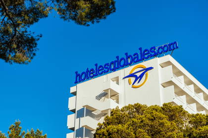 Biały budynek hotelu z niebieskim logo "hotelesglobales.com".