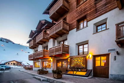 Hotel z drewnianymi balkonami na tle ośnieżonego stoku.