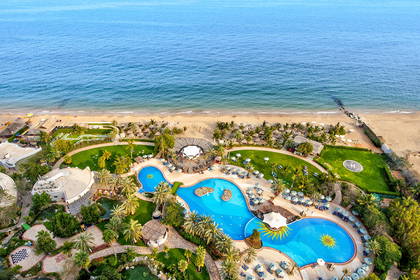 Hotel z basenami i plażą widziany z góry.