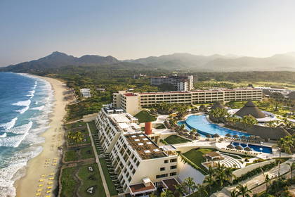 Kompleks hotelowy z basenami przy plaży, widok z góry. W tle góry.