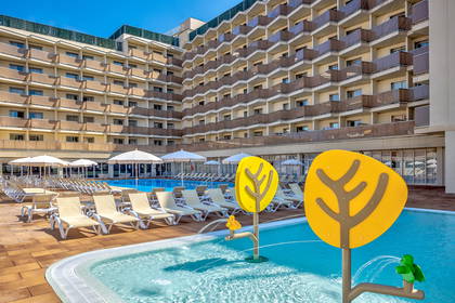 Hotelowy basen z fontannami dla dzieci i leżakami do opalania.