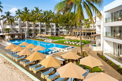 Luksusowy hotel z basenem, leżakami i palmami.