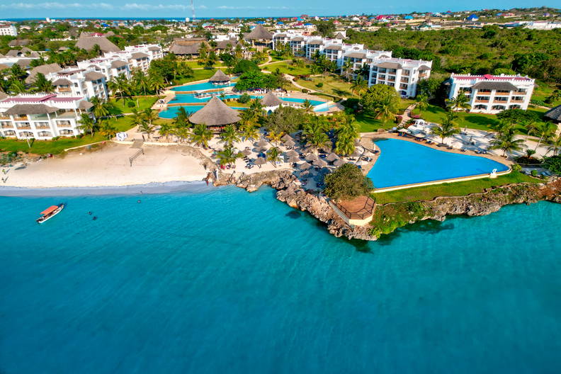 Widok z lotu ptaka na tropikalny kurort z basenami i plażą.