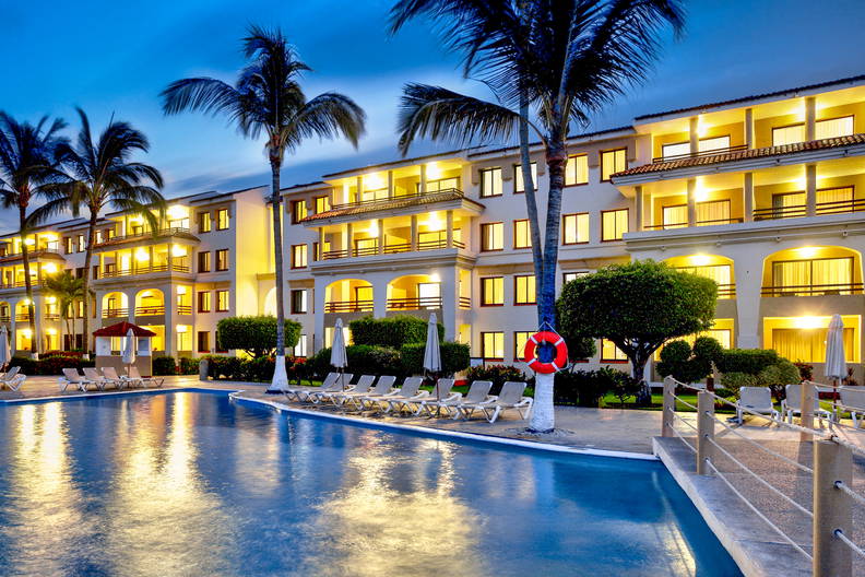 Hotel z basenem i palmami o zmierzchu.