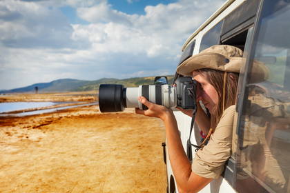 Kobieta w kapeluszu fotografuje z samochodu safari.