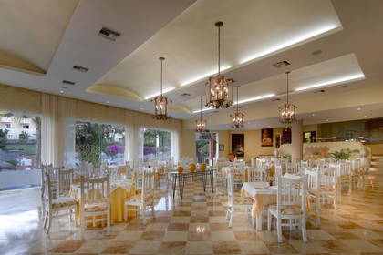 Jasne wnętrze restauracji z białymi krzesłami i marmurową podłogą.