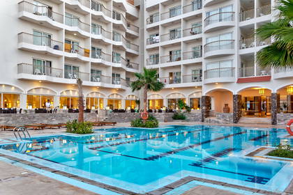 Kompleks hotelowy z basenem w słoneczny dzień.