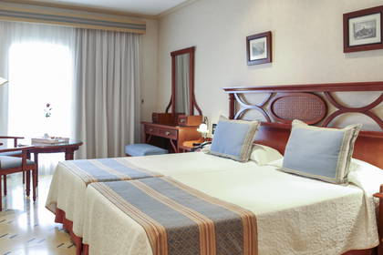 Pokój hotelowy z dwoma łóżkami, toaletką i stolikiem.