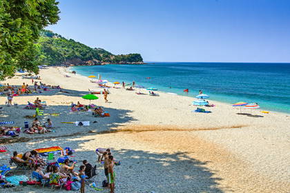 Plaża z parasolami i wypoczywającymi ludźmi. W tle morze.