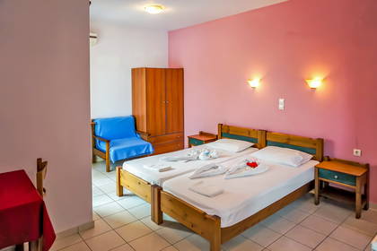 Pokój hotelowy z dwoma łóżkami i fotelem.