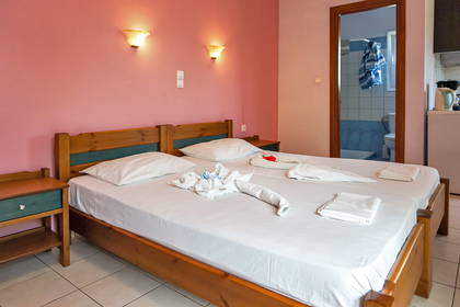 Pokój hotelowy z dwoma łóżkami i otwartymi drzwiami do łazienki.