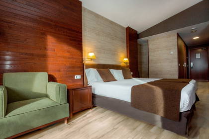 Pokój hotelowy z łóżkiem, szafką nocną i zielonym fotelem.