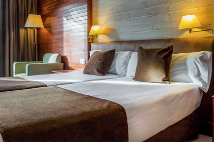 Pokój hotelowy z dwoma łóżkami i lampkami nocnymi.
