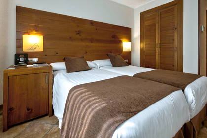 Pokój hotelowy z dwoma łóżkami, szafką nocną i szafą.