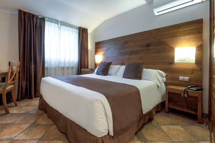 Pokój hotelowy z dużym łóżkiem i drewnianym zagłówkiem.