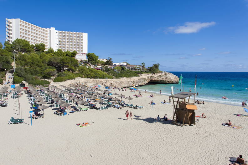 Plaża z parasolami, leżakami i wieżą ratownika.