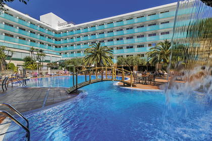 Kompleks hotelowy z basenem i drewnianym mostkiem.