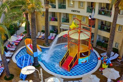 Widok z góry na hotelowy aquapark z palmami i zjeżdżalniami.