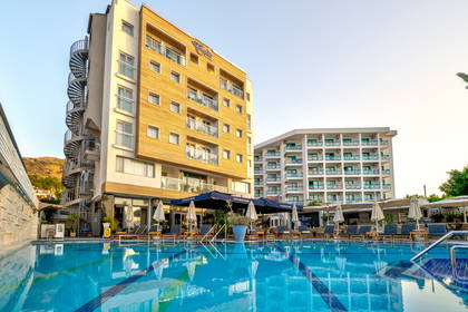 Nowoczesny hotel, a na pierwszym planie duży basen z leżakami.