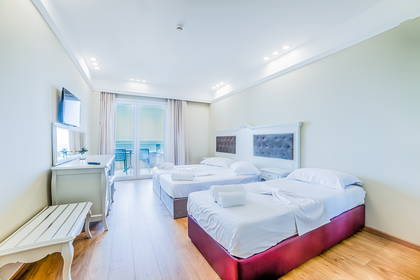 Jasny pokój hotelowy z dwoma łóżkami, komodą i balkonem.
