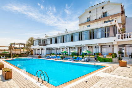 Hotel z basenem, leżakami i parasolami w słoneczny dzień.